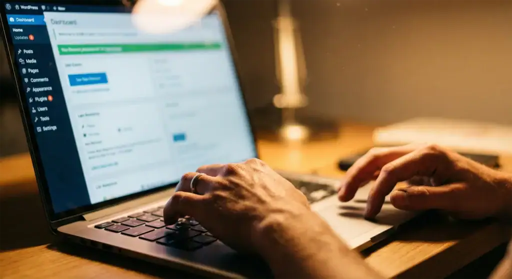 Dłonie developera pracującego na laptopie w kokpicie WordPressa, ekran rozmyty